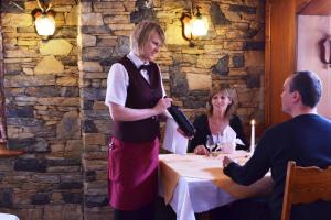 a woman is standing at a table holding a wine bottle at Hotel Alpenblick-Leukerbad-Therme in Leukerbad