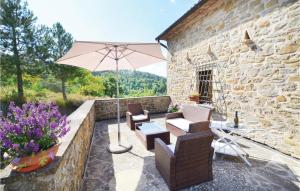 un patio con sillas, una mesa y una sombrilla en Amazing Home In Apecchio -pu- With Kitchen, en Apecchio