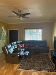 a living room with a leather couch and a ceiling fan at paradise cove in Spanish Town