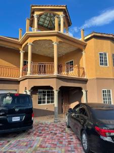 two cars parked in front of a large house at paradise cove in Spanish Town