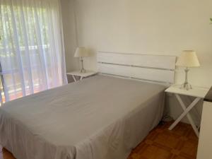 a white bed in a room with two tables and a window at Monoambiente con cochera. Excelente ubicación. in Mar del Plata
