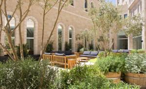 a courtyard with furniture and trees in front of a building at Mamilla Hotel in Jerusalem +46 photos