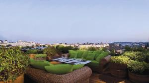 a patio with green furniture and a table on a roof at Mamilla Hotel in Jerusalem