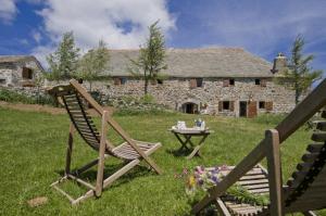 a chair and a table in front of a stone house at Le Francillon in Les Estables