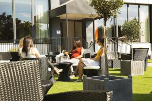 three women sitting in chairs outside of a building at Executive Hôtel Paris Gennevilliers in Gennevilliers