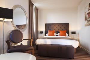 ein Schlafzimmer mit einem Bett, einem Stuhl und einem Spiegel in der Unterkunft Executive Hôtel Paris Gennevilliers in Gennevilliers