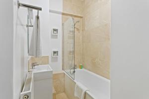 une salle de bain avec une baignoire blanche et un lavabo dans l'établissement Trendy 1 Bedroom Apartment in the Heart of London, à Londres