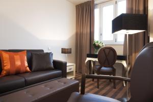 a living room with a couch and a chair at Executive Hôtel Paris Gennevilliers in Gennevilliers