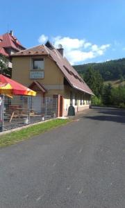a building with a table and an umbrella on the side of the road at Penzion U Štoly Jáchymov in Jáchymov