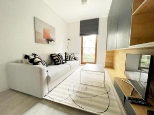 ein Wohnzimmer mit einem weißen Sofa und einem TV in der Unterkunft Comfy Apartments - Sopocka Rezydencja in Sopot