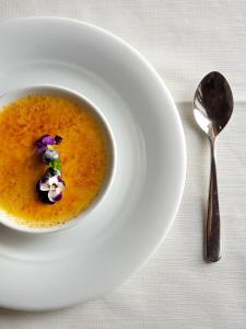 un bol de soupe sur une assiette blanche avec une cuillère dans l'établissement Fracanzana Hotel, à Montebello Vicentino