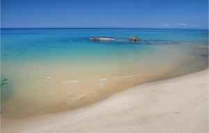 a sandy beach with a small island in the water at Gorgeous Apartment In Costa Rei -Ca- With Wifi in Costa Rei