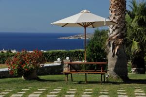 a bench under an umbrella next to a palm tree at Fragoulis Village in Parasporos