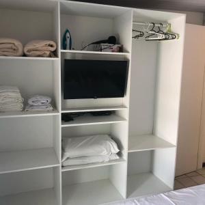 un estante de libros blanco con un televisor. en Ancorar Flat - dois quartos, en Porto de Galinhas