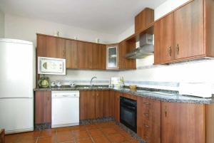 una cucina con armadi in legno e frigorifero bianco di Casa Verano a Mijas