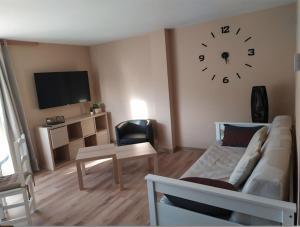 sala de estar con sofá y reloj en la pared en CHECK-IN CASAS El rinconet, en Cerler