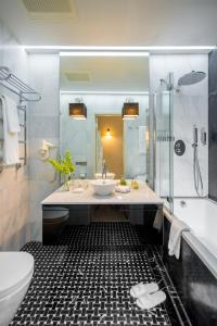a bathroom with a sink and a tub and a toilet at Astoria Hotel in Lviv