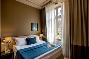 a bedroom with a bed with blue sheets and a window at Astoria Hotel in Lviv