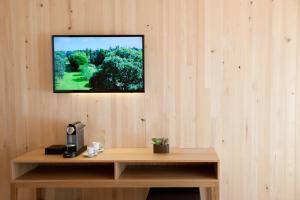 a television hanging on a wall with a wooden desk at Hotel am Garnmarkt in Götzis