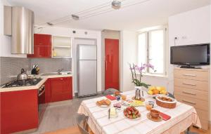 una cucina con armadi rossi e un tavolo con cibo di Casa Capestalozzi a Chiavenna Altre 11 foto