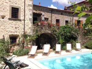 a group of chairs sitting next to a pool at Palazzo del Duca in Tavernelle