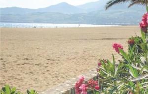 a view of the beach with pink flowers in the foreground at Cozy Apartment In Vinassan With Wifi in Vinassan