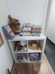 een witte boekenplank met knuffels en boeken bij Mini Apartamento de Lujo in Becerril de la Sierra