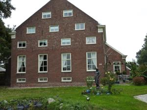 un gran edificio de ladrillo con una estatua delante de él en Wellness Sauna Beauty Farm Midwolda, en Midwolda