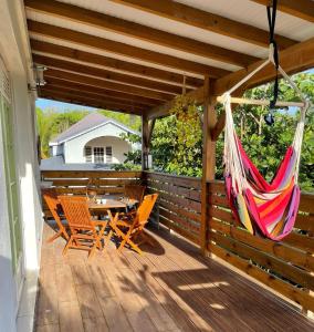 a porch with a hammock and a table and chairs at Charmant bungalow du Moule in Le Moule