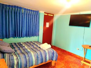 a bedroom with a bed and a flat screen tv at Vacahouse Hostel - Huaraz in Huaraz