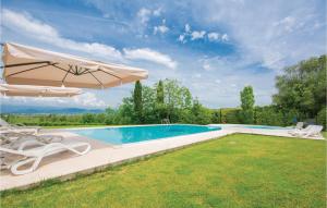 a swimming pool with an umbrella and two lawn chairs and a pool at Gardenia in Cerreto Guidi