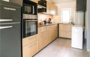 cocina con armarios de madera y nevera negra en Lovely Home In St Urbain With Kitchen, en Saint-Urbain
