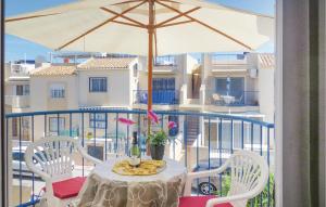 una mesa y sillas en un balcón con sombrilla en Amazing Apartment In Torrevieja With Kitchen, en Torrevieja
