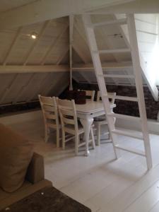 une salle à manger avec une table et des chaises blanches dans l'établissement Attic Room Judy's, à Zandvoort
