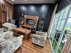 a living room with two chairs and a television at EagleNest at Iris House Resort in Tanah Rata