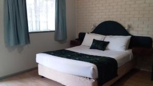 sypialnia z dużym białym łóżkiem z czarnym zagłówkiem w obiekcie Macquarie Valley Motor Inn w mieście Warren
