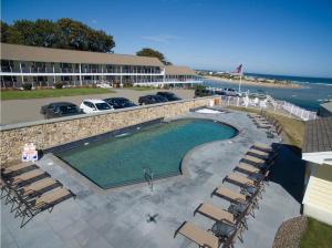 a swimming pool with chairs and a hotel and the ocean at Sea Chambers in Ogunquit