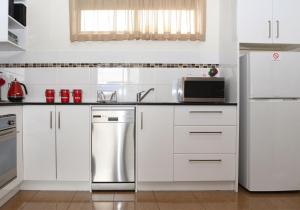 La cuisine est équipée de placards blancs et d'un réfrigérateur en acier inoxydable. dans l'établissement Dromana Beach Getaway, à Dromana