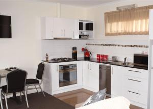 a kitchen with white cabinets and a table and chairs at Dromana Beach Getaway in Dromana