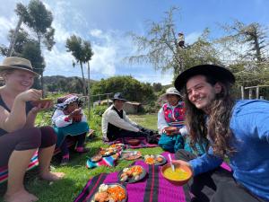 un gruppo di persone seduti su una coperta da picnic con cibo di Richar’s home - experience Amantani with my family a Ocosuyo
