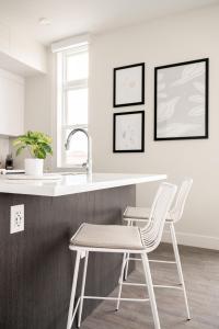 una cucina con due sedie bianche e un lavandino di A Modern Point of View - Luxe Loft - Espadin LoHi a Denver