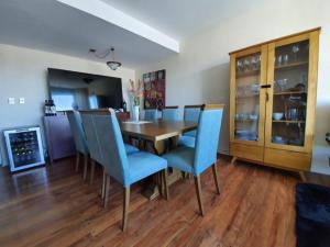 uma sala de jantar com uma mesa de madeira e cadeiras azuis em Mendoza Premium Suites - Dpto de Lujo Piso 14 - Vista A La Montaña! em Mendoza