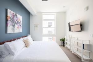 Skyline Blue Modern Loft - Zuni Lofts في دنفر: غرفة نوم بسرير ابيض وتلفزيون