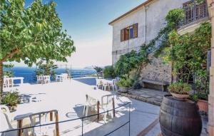eine Terrasse mit einem Tisch, Stühlen und Meerblick in der Unterkunft Cozy Apartment In Gioiosa Marea Me With Kitchenette in San Giorgio