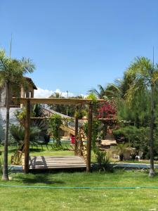 a wooden pergola in a park with a playground at Pousada farol in Areia Branca