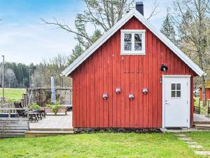 a red barn with a white door in a yard at Holiday home PÅRYD in Påryd