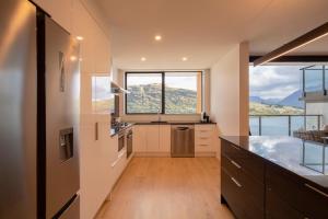 cocina con armarios blancos y ventana grande en 4 Bedroom Home with elevated views of Lake Wakatipu & The Remarkables, en Queenstown