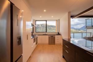 Una cocina con gabinetes blancos y una ventana grande. en 4 Bedroom Home with elevated views of Lake Wakatipu & The Remarkables, en Queenstown