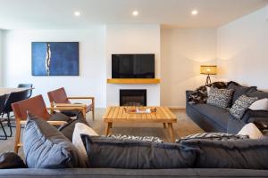 sala de estar con sofás, mesa y TV en 4 Bedroom Home with elevated views of Lake Wakatipu & The Remarkables, en Queenstown