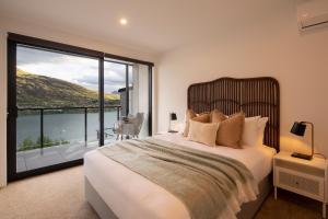 Un dormitorio con una cama grande y una ventana grande. en 4 Bedroom Home with elevated views of Lake Wakatipu & The Remarkables, en Queenstown